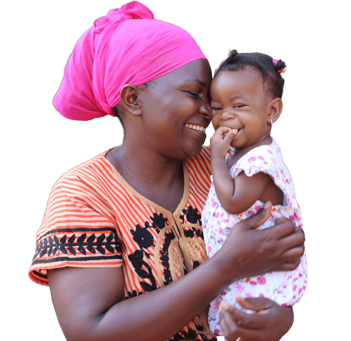 A toddler Ugandan girl is being held by her foster mother who lovingly nudges the girls face with her own. The girl laughs while sucking her fingers.