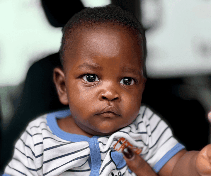 A Ugandan baby in a white and blue striped onesie