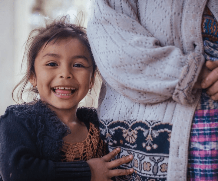 Guatemalan girl stands by the hip of her mother