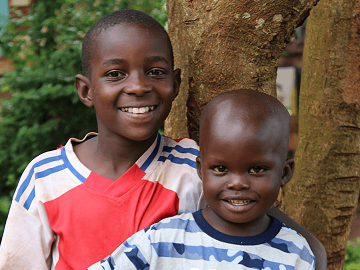 A young boy smiles with his older foster brother in LWB's Uganda foster care program