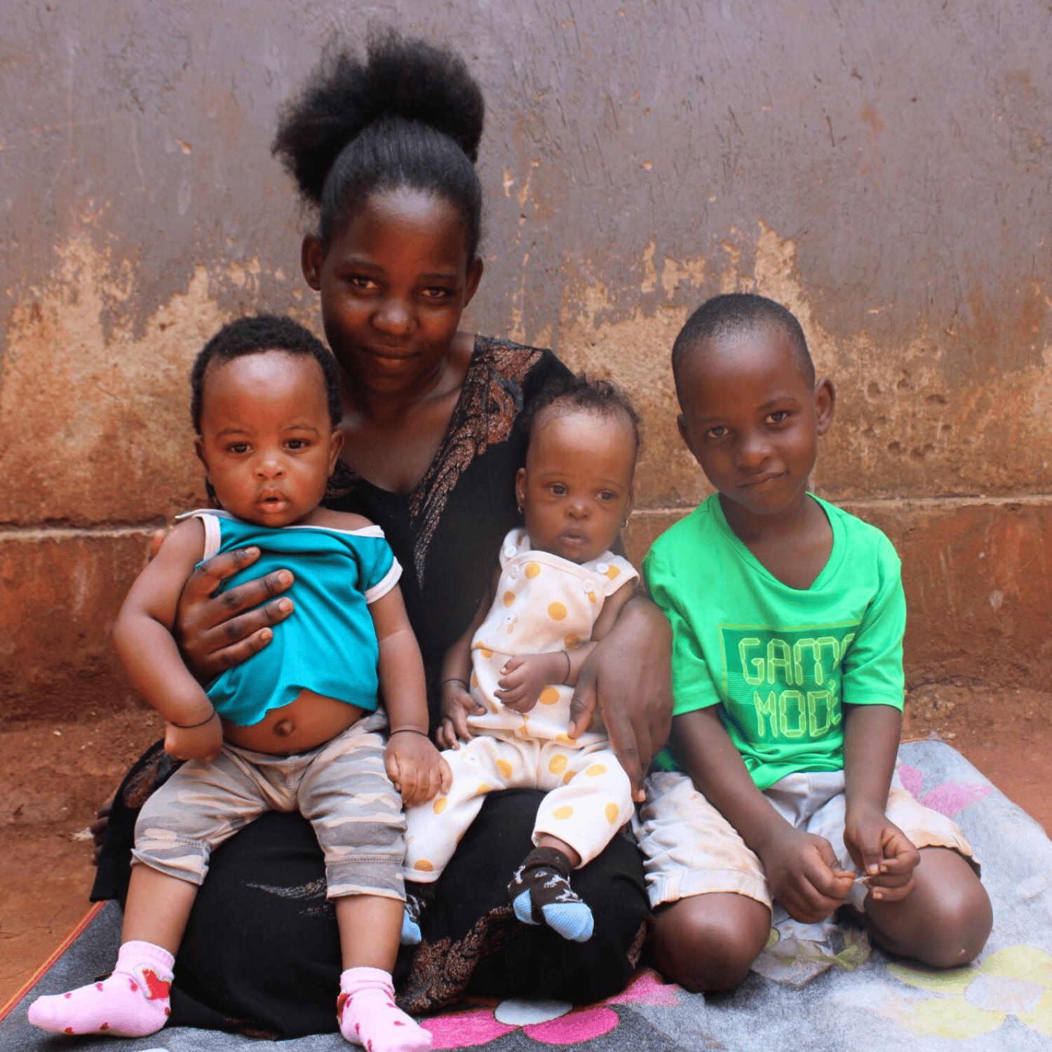 A baby girl in LWB's cardiac program sits on the lap of her mother in between her twin brother and elder brother.