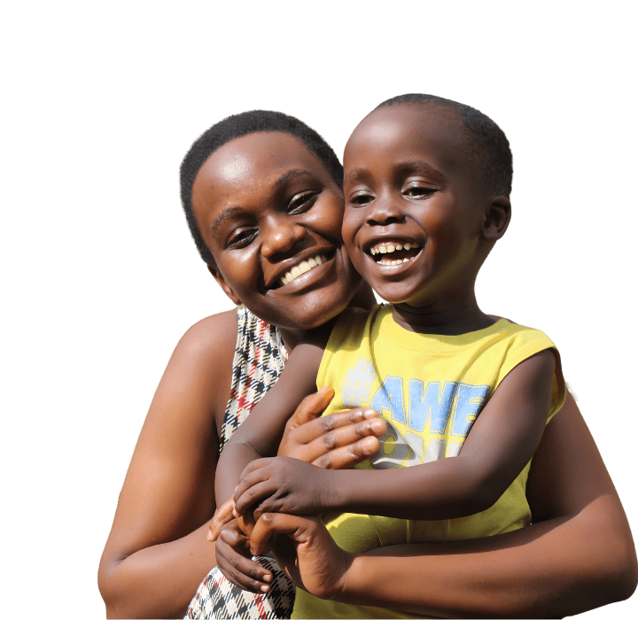 A preschool-aged boy from Uganda laughs in the arms of his foster mother. He wears a yellow shirt, while she wears a black, red, and white plaid dress. 