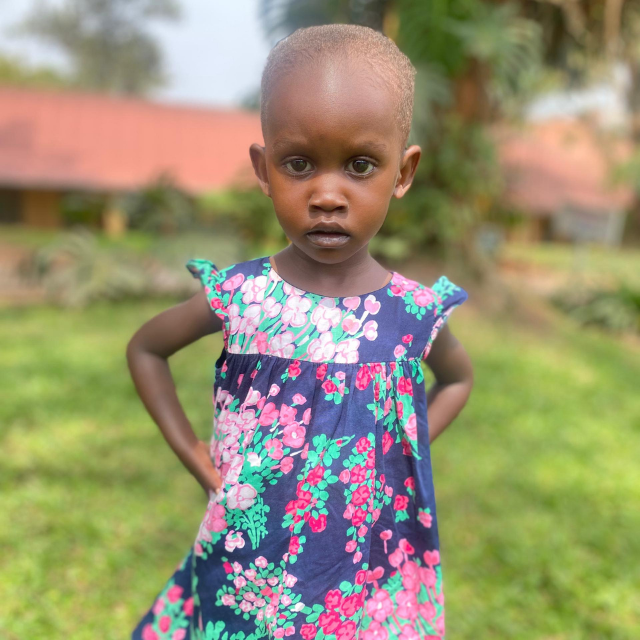 A young Ugandan girl with a heart defect wears a beautiful flower dress.