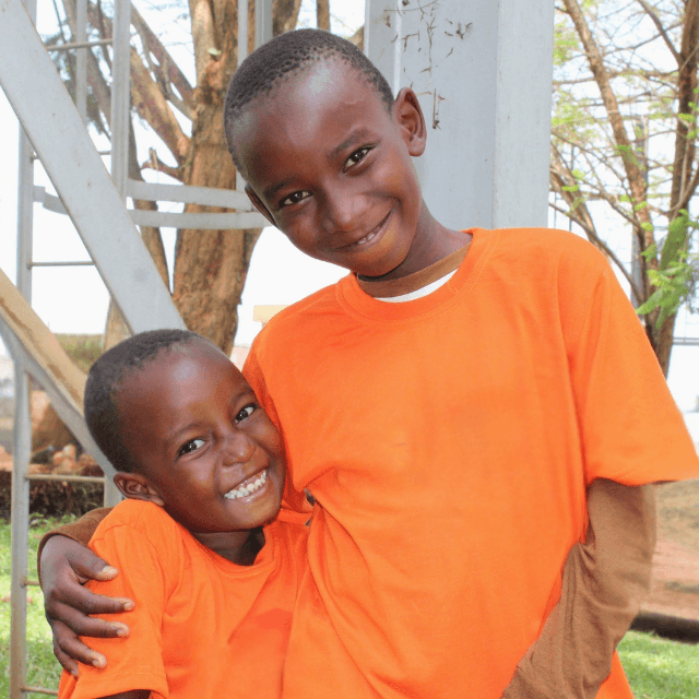 Two smiling boys hugging each other at LWB's hernia mission.