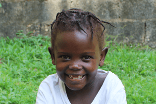 Ugandan girl in LWB's Cardiac Program smiles with her two front teeth missing.