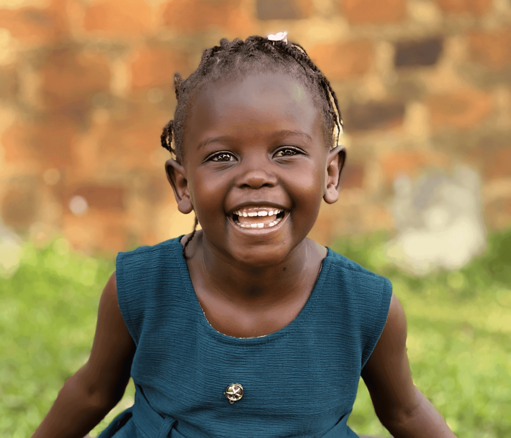 Mary's joy shines brightly through her eyes and her smile. She is a Ugandan girl dressed in a beautiful blue dress with silver star buttons. Her hair is braided