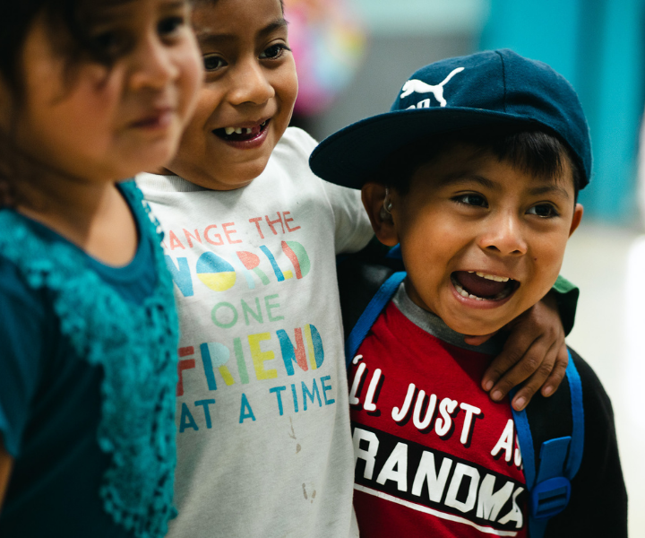 Two girls and a boy are in a big hug together as they laugh together.